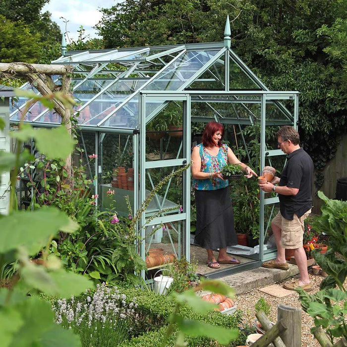 Man and woman potting plants besides their Rhino Greenhouse