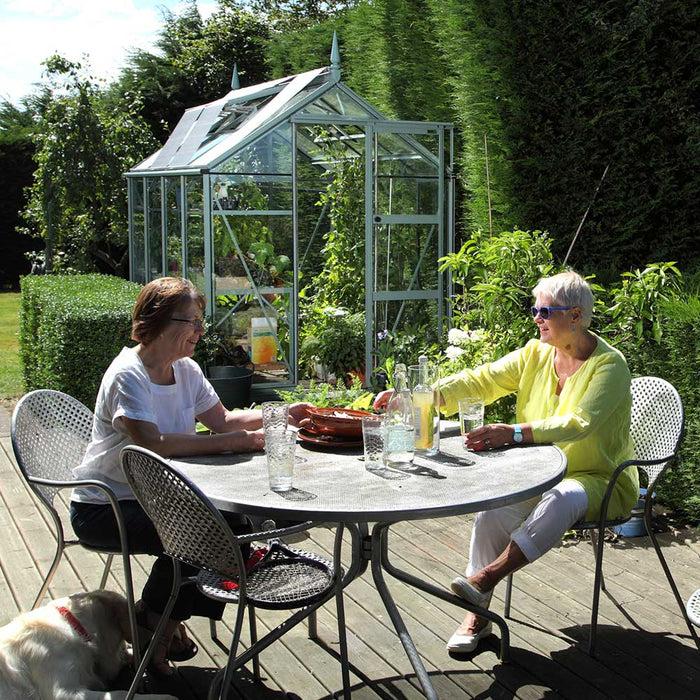 Two ladies sat at table with a Rhino greenhouse in background